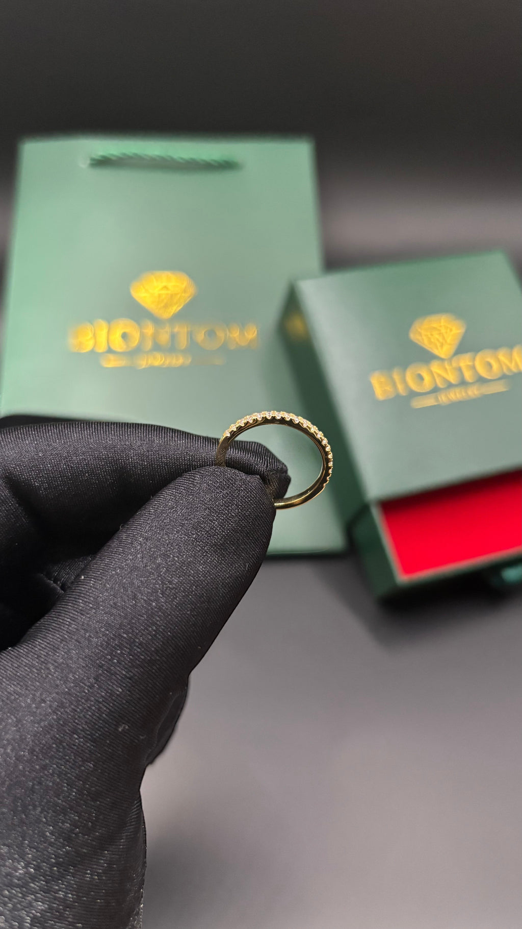 BIONTOMのゴールドメッキ仕上げの繊細なモアサナイトリング。ギフトボックスとショッパーが背景に写る高級感あるデザイン。